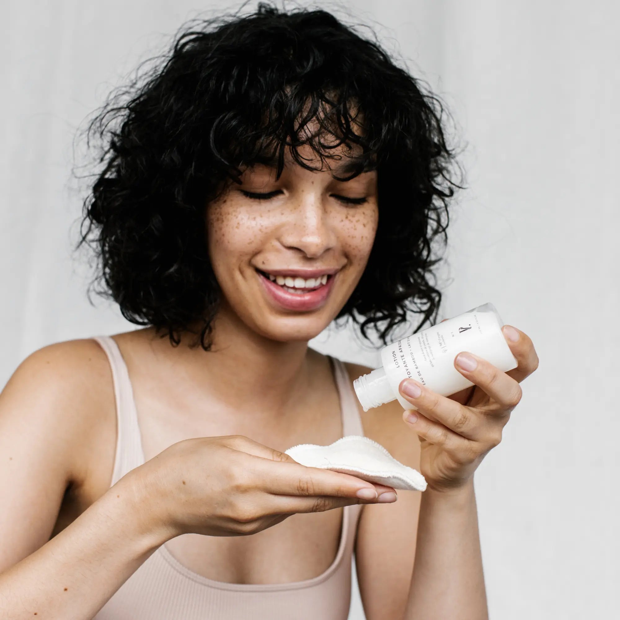 femme appliquant lotion visage sur coton